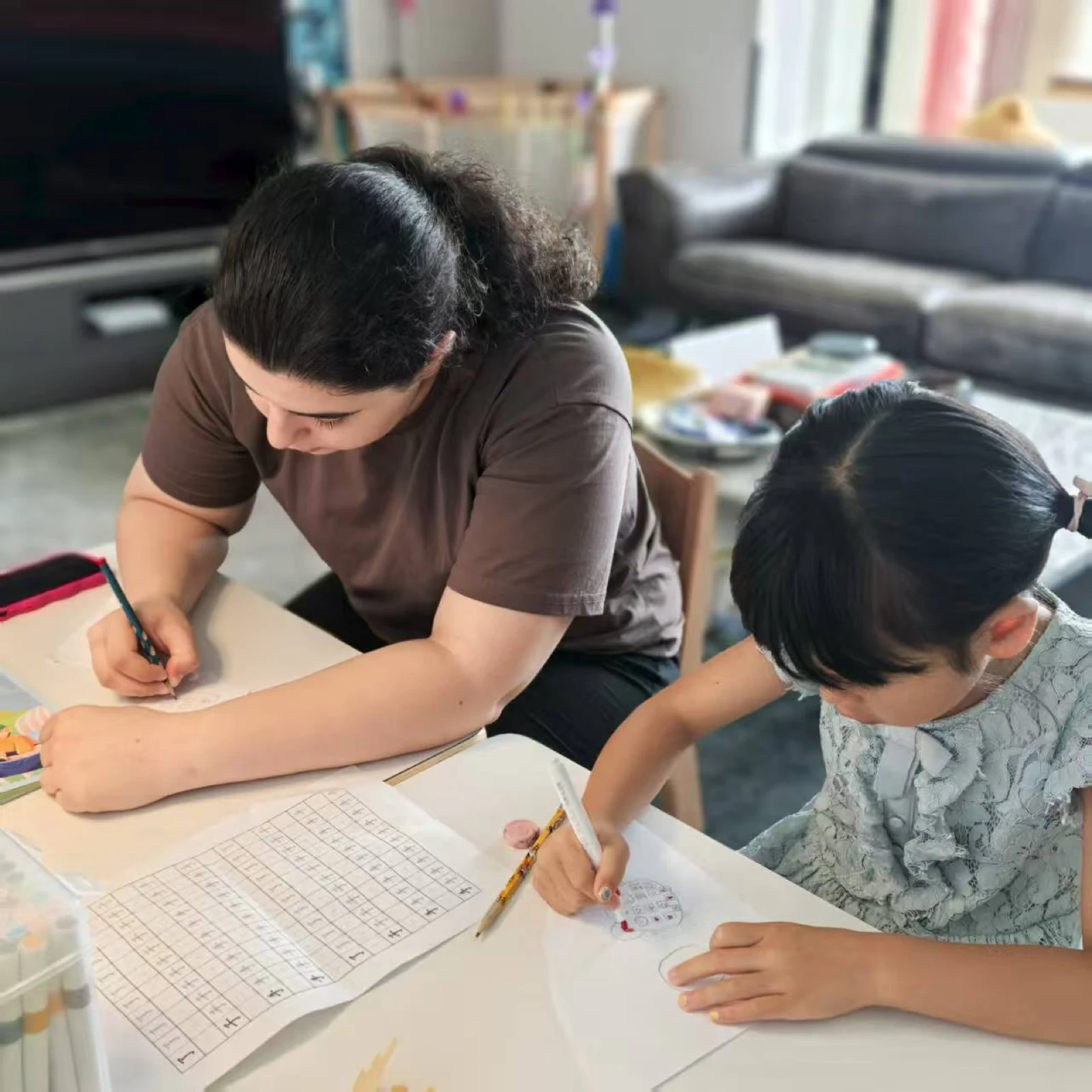An au pair and a child drawing and practising Chinese characters together at home