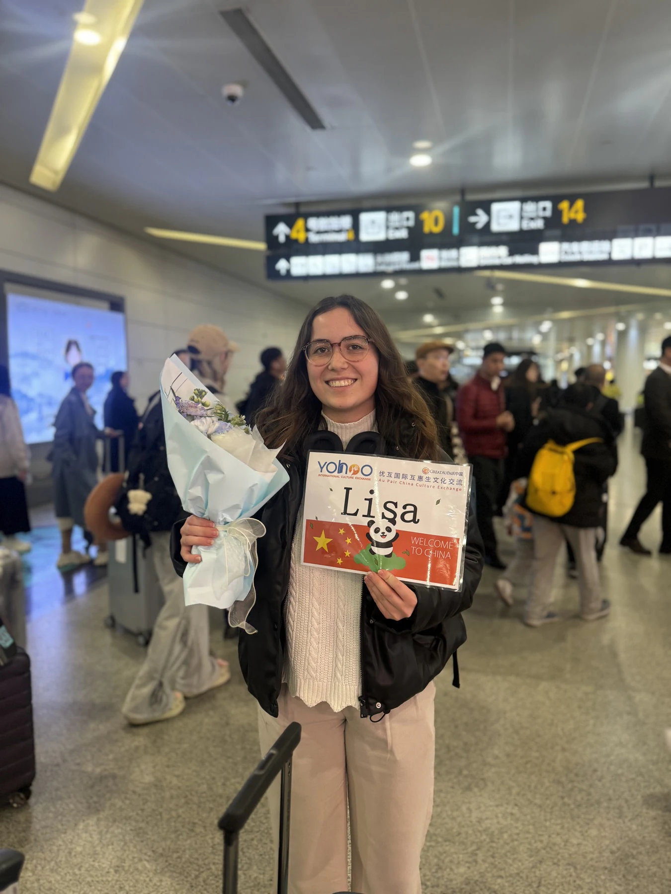 Au pair Lisa arriving in China with flowers and a personalised Yohoo welcome sign